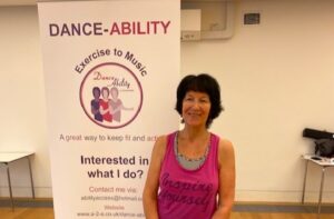 woman stands with a dance ability sign behind her