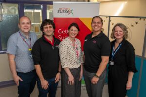 five people look at the camera standing in front of a Active Sussex banner