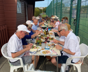 people dressed in tennis whites sit at a table enjoying a meal
