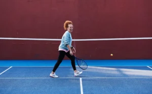 person playing tennis on a blue court