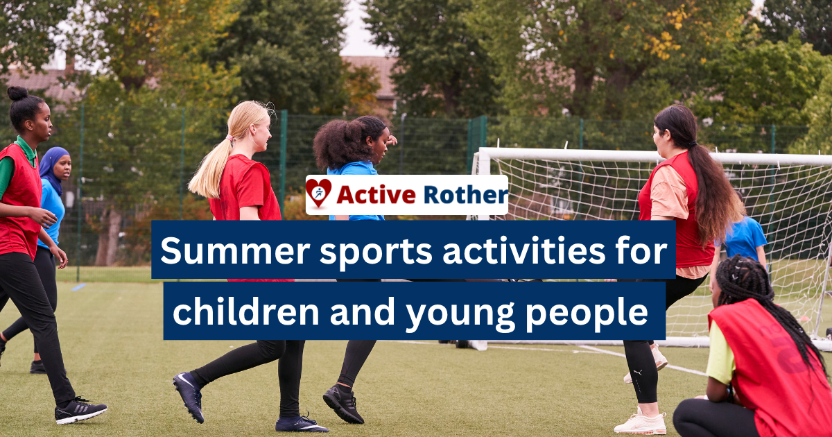 A group of girls take part in summer holiday activities, playing football on an open fields in Rother East Sussex